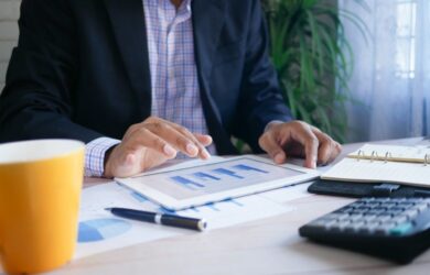 Yrittäjä tarkastelee talouskaaviota tabletilla työpöydän ääressä