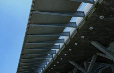 Modernin rakennuksen julkisivun yksityiskohta metallirakenteista ja betonista sinistä taivasta vasten.